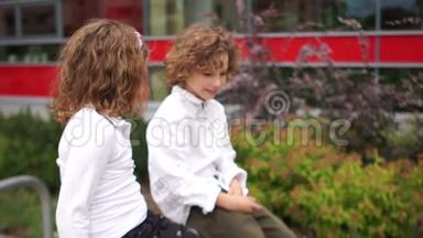 一个男孩和一个女孩坐在学校附近的栏杆上，互相看着。 学校友谊